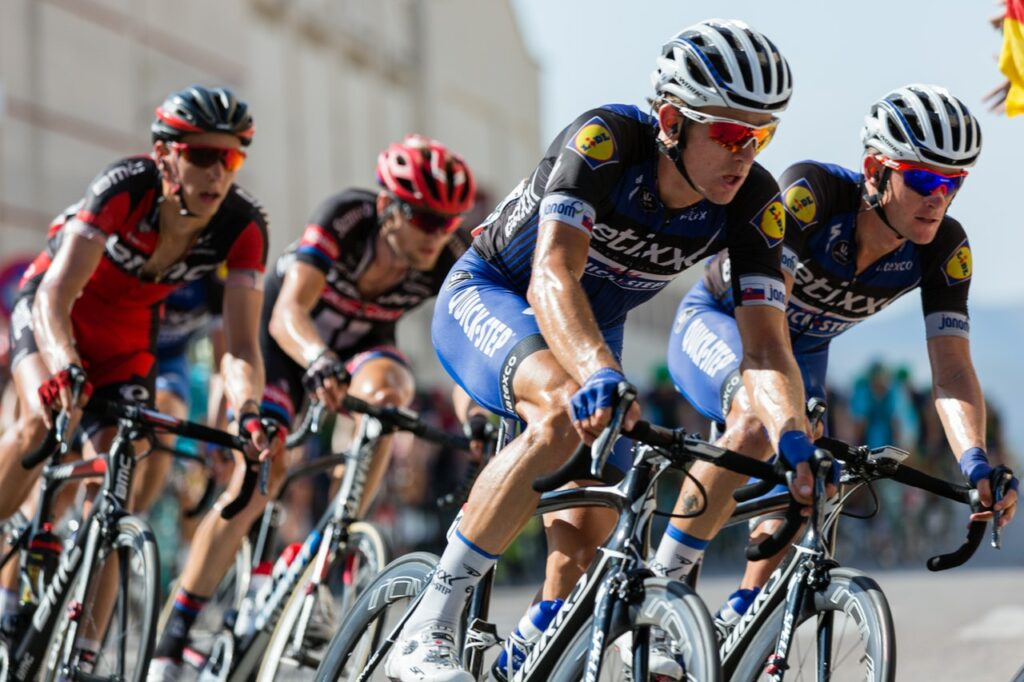 Professional cyclists racing in a group, wearing helmets and cycling gear, demonstrating high-performance road bikes available at our cycle shop.